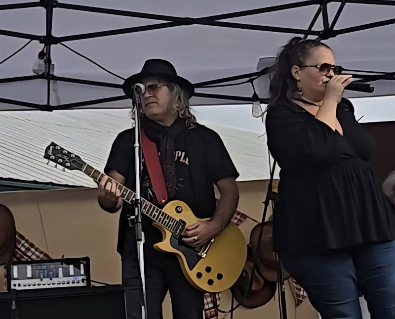Guitarist and singer performing on a tented outdoor stage