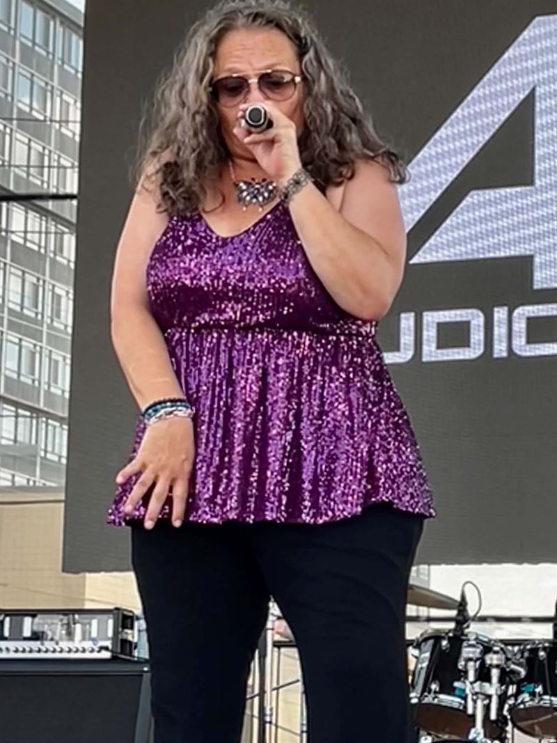 Lead singer in a purple sequinned top performing outdoors